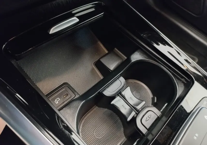 Gros plan sur la console centrale noire brillante avec porte-gobelets et port USB de la Mercedes GLA 200 Business Line.