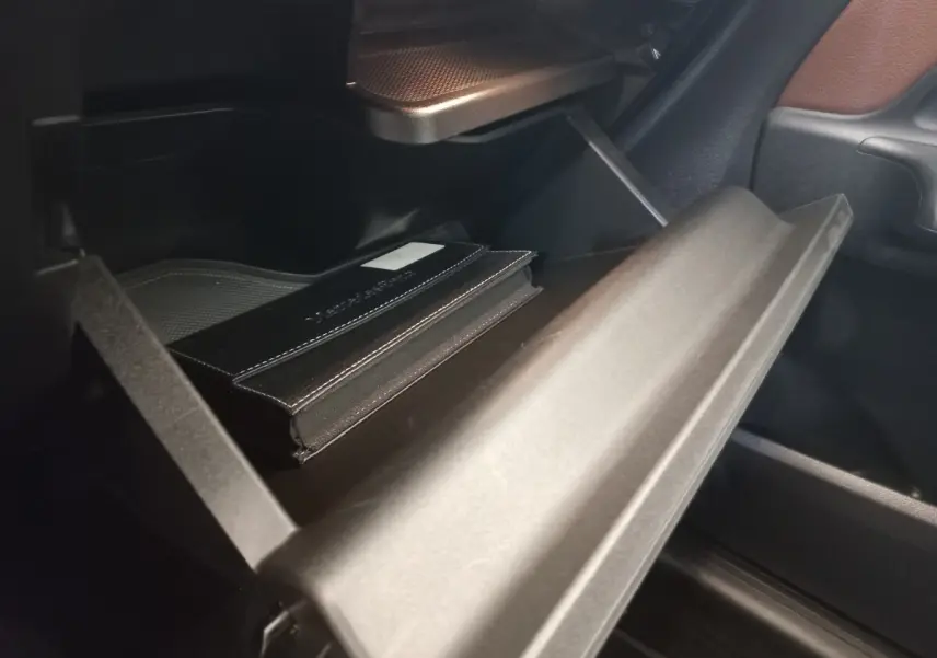 Gros plan sur la boîte à gants ouverte de la Mercedes GLA 200 Business Line 2021, avec un carnet noir à l'intérieur.