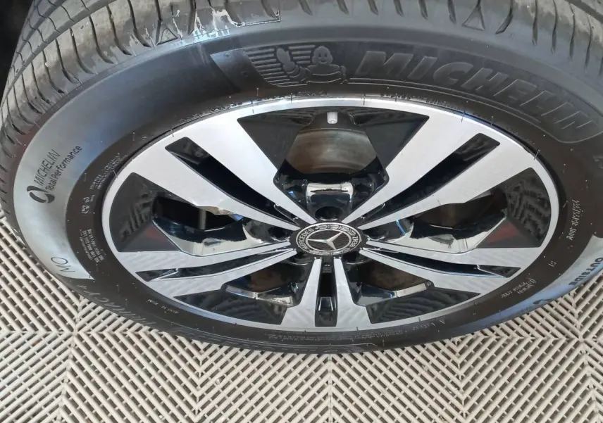 Gros plan sur la jante alliage bicolore noire et argentée d'un Mercedes GLA gris foncé, pneu Michelin visible.