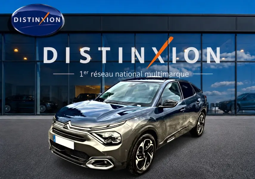 Citroën C4 gris vue 3/4 avant droit, avec jantes alliage et calandre distinctive, devant showroom Distinxion.