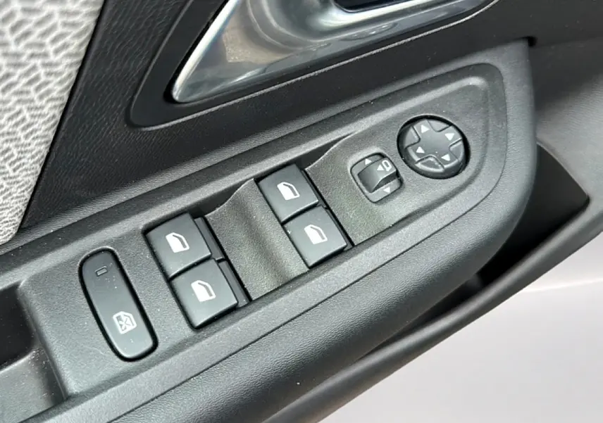 Gros plan sur les commandes de lève-vitres et réglages des rétroviseurs côté gauche d'une Citroën C4 gris.