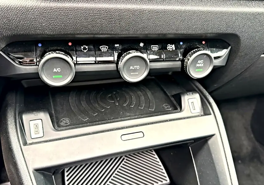 Détail de la console centrale noire avec commandes de climatisation automatique et recharge sans fil dans une Citroën C4 gris 2024.