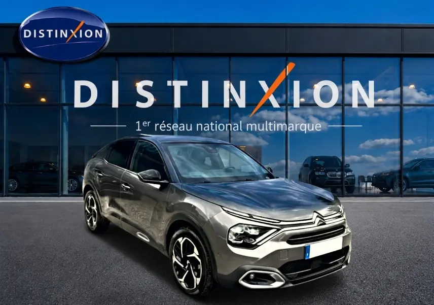 Citroën C4 gris 3/4 avant droit, avec jantes alu et calandre distinctive, devant vitrine Distinxion.