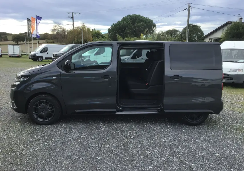 Vue latérale gauche d'un Citroën Jumpy gris titane avec porte coulissante ouverte révélant les sièges arrière noirs.