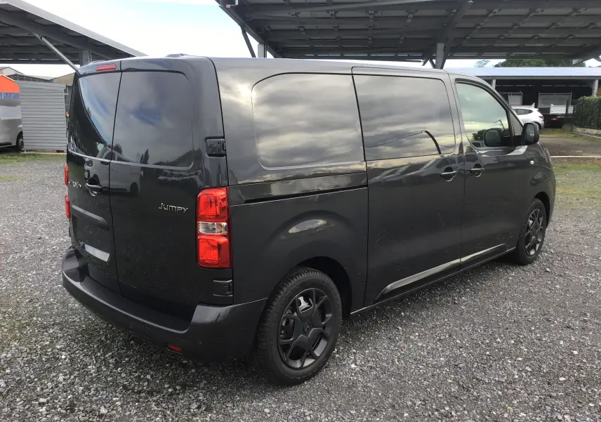 Vue 3/4 arrière droite d'un Citroën Jumpy cabine approfondie gris titane avec vitres arrière opaques et jantes noires.