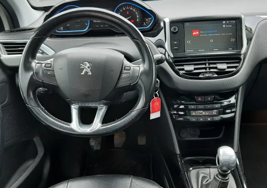 Vue intérieure du tableau de bord et volant cuir noir du Peugeot 2008 2017 avec écran tactile et levier de vitesses manuel.