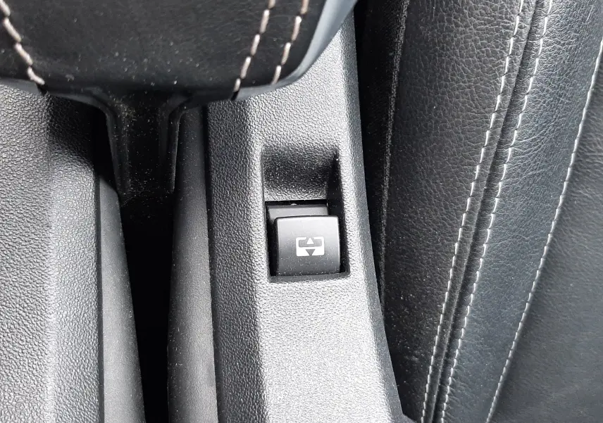 Bouton de commande de lève-vitre électrique sur la console centrale en cuir noir du Peugeot 2008 blanc de 2017.