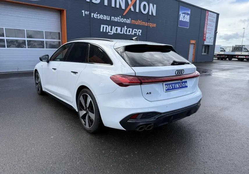 Audi A5 Avant blanc glacier métallisé vue 3/4 arrière droit avec jantes noires et feux arrière LED connectés.