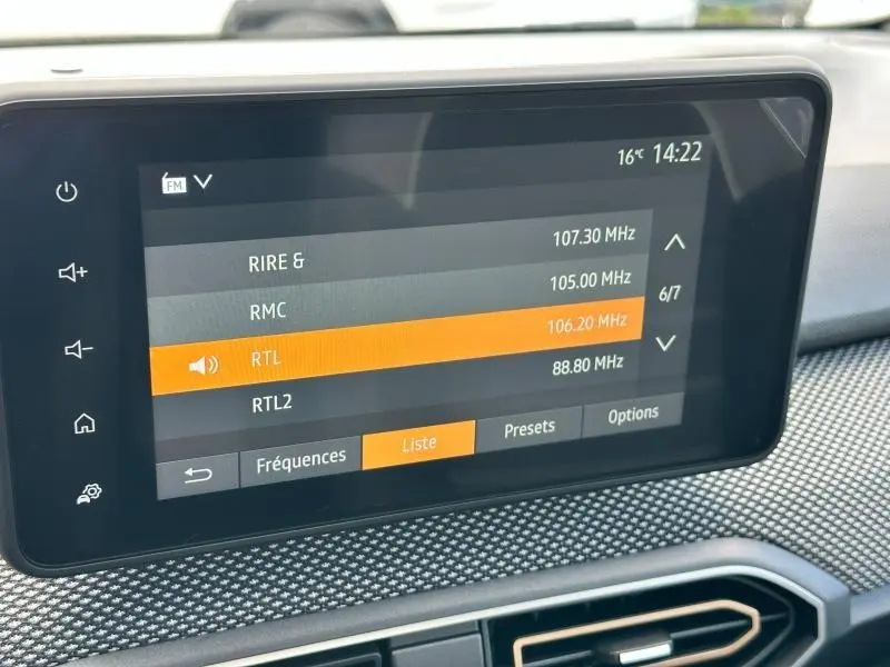 Écran tactile central affichant les stations radio FM dans l'habitacle d'une Dacia Sandero blanche 2025.