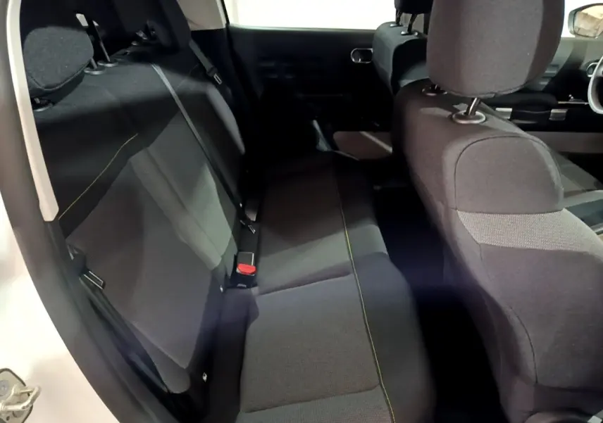 Vue intérieure côté gauche montrant la banquette arrière noire avec surpiqûres jaunes d'une Citroën C3 blanche 2023.