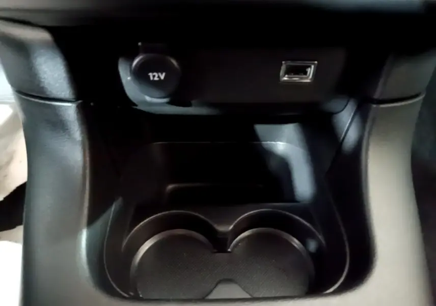 Gros plan sur la console centrale noire de la Citroën C3 Shine 2023, avec prise 12V et port USB visibles.