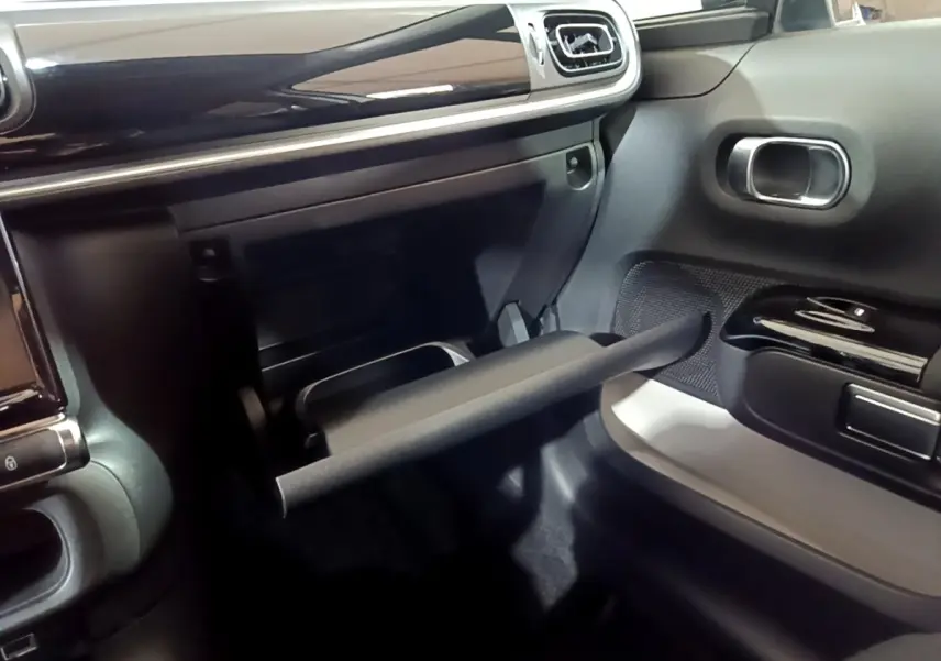 Intérieur côté passager de la Citroën C3 blanche 2023, avec boîte à gants ouverte et tableau de bord noir brillant.