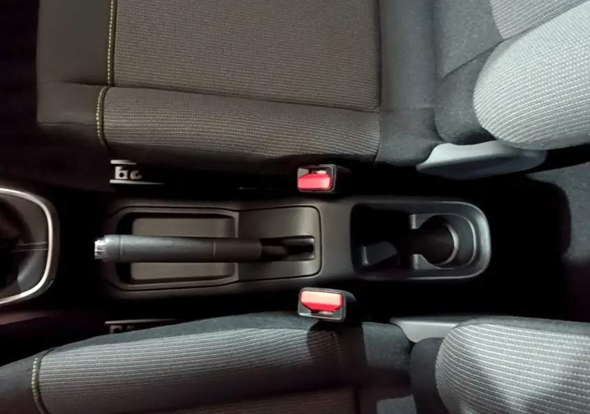 Vue plongeante sur la console centrale noire et les sièges tissu gris avec coutures jaunes de la Citroën C3 blanche 2023.