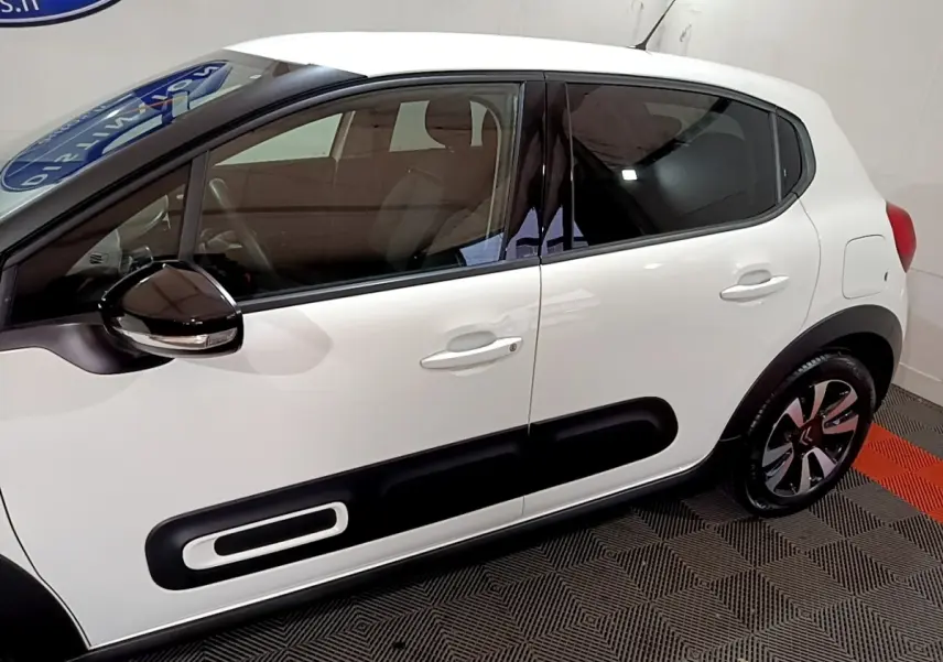 Profil côté gauche d'une Citroën C3 blanche avec protections latérales noires et jantes bicolores modernes