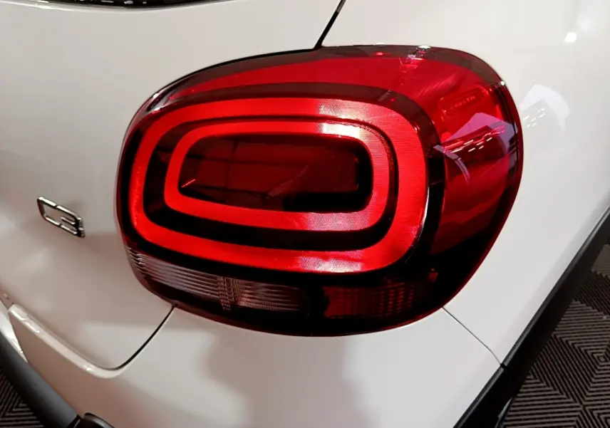 Gros plan sur le feu arrière droit rouge d'une Citroën C3 blanche 2023 avec logo C3 visible sur la carrosserie.