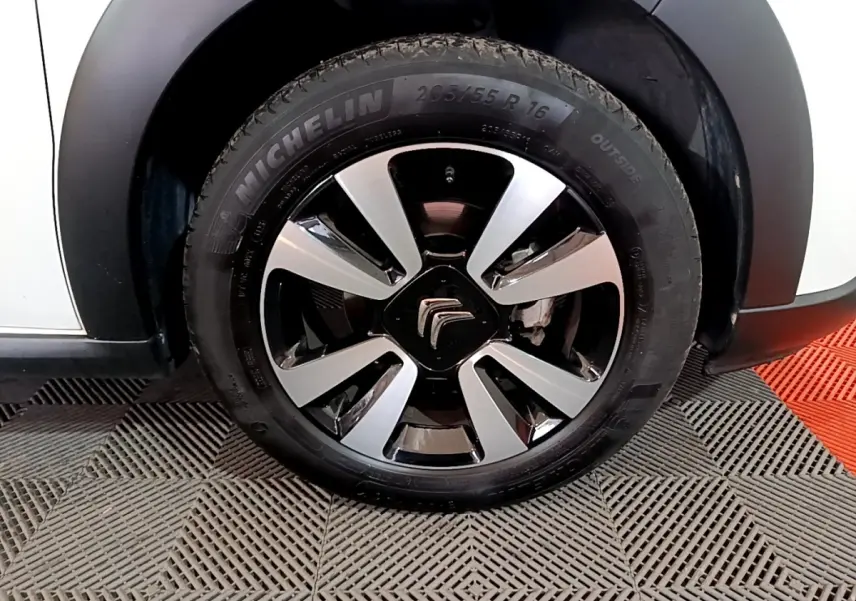 Gros plan sur la roue avant gauche d'une Citroën C3 blanche avec jante alliage bicolore et pneu Michelin.