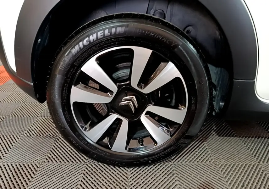 Gros plan sur la roue avant gauche d'une Citroën C3 blanche avec jante alliage bicolore et pneu Michelin.
