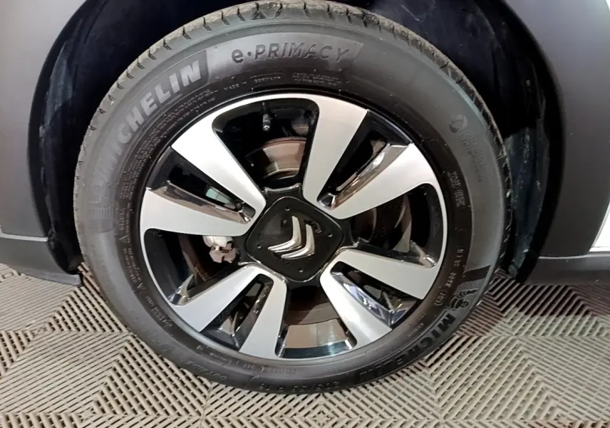 Gros plan sur la jante alliage bicolore avec logo Citroën au centre d'une roue Michelin d'une Citroën C3 blanche.