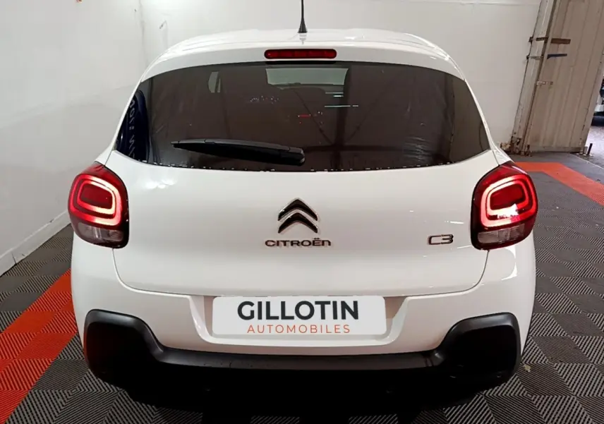 Vue arrière d'une Citroën C3 blanche 2023 avec feux arrière LED et logo centré sur un sol à damier noir et orange.