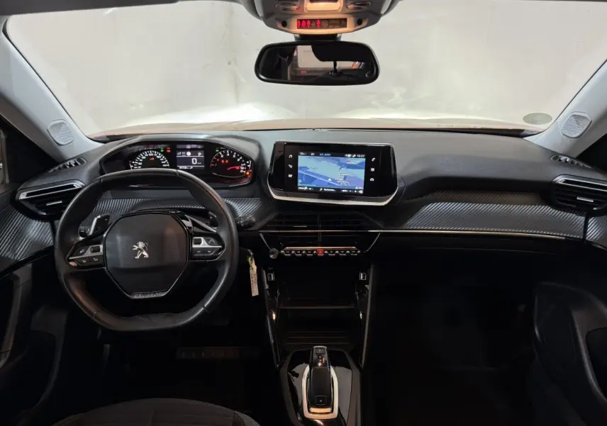 Vue intérieure frontale du tableau de bord noir de la Peugeot 2008 avec écran tactile central et volant multifonctions.