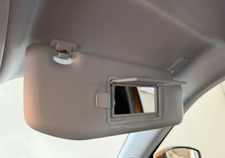 Détail intérieur montrant le pare-soleil gris avec miroir intégré côté conducteur d’un Peugeot 2008 orange.