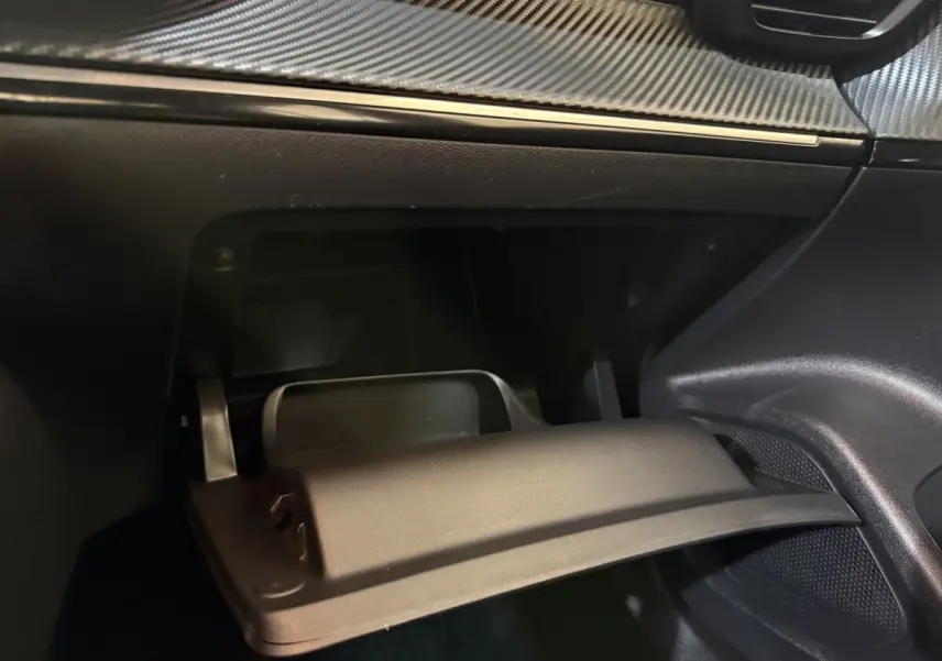 Gros plan sur la boîte à gants ouverte du Peugeot 2008 2022, intérieur noir avec finition effet carbone.