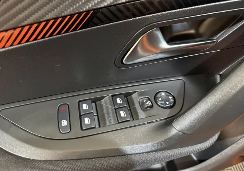 Gros plan sur la commande des vitres et rétroviseurs côté gauche d’une Peugeot 2008 orange, intérieur noir.