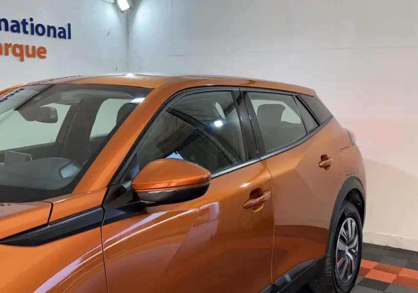 Vue de profil côté gauche d’un Peugeot 2008 orange 2022 avec rétroviseur et poignées assortis.
