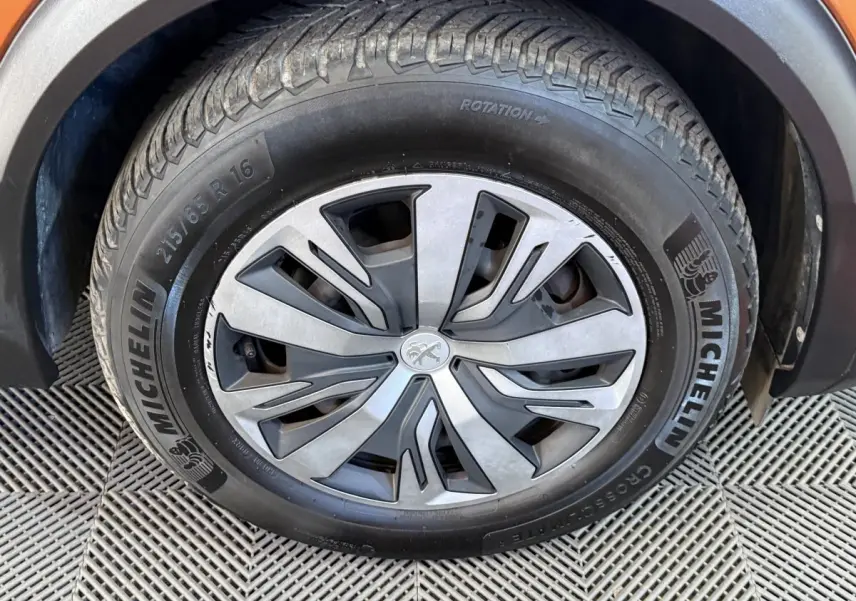 Gros plan sur la roue avant droite d’un Peugeot 2008 orange, avec jante alliage et pneu Michelin visible.