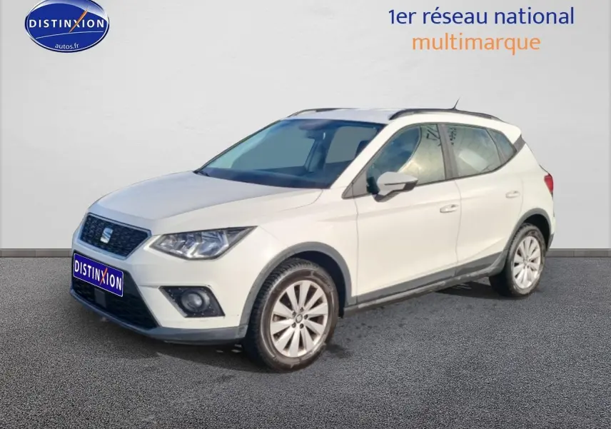 SEAT Arona blanc vue 3/4 avant droit, avec jantes alliage et barres de toit noires visibles.
