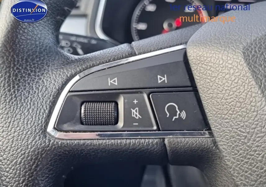 Gros plan sur les commandes audio et vocales sur le volant cuir d'une SEAT Arona blanche de 2019.