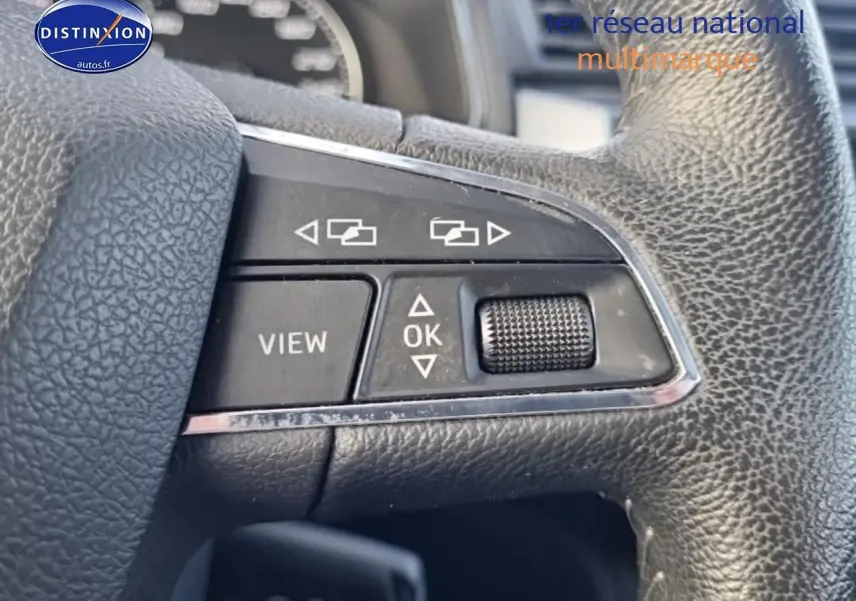Gros plan sur les commandes multifonctions en cuir noir du volant d’un SEAT Arona blanc, version 2019.