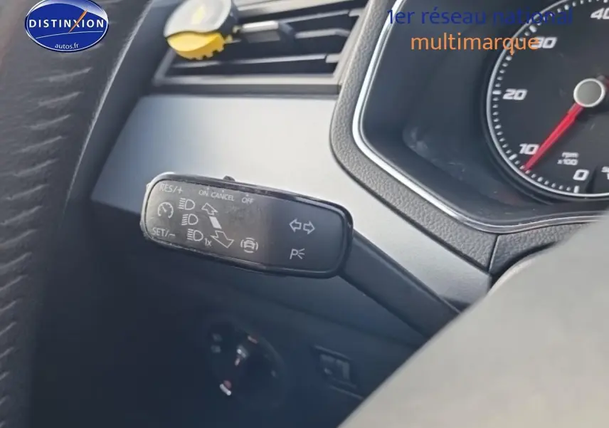 Gros plan sur la manette de commande multifonction noire à gauche du volant dans l'habitacle d'une SEAT Arona blanche.