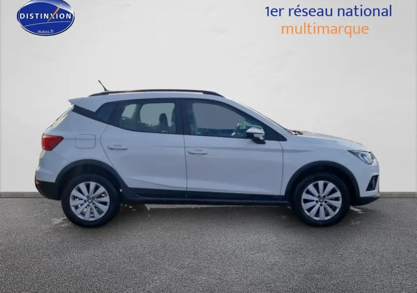 Vue de profil côté gauche d’un SEAT Arona blanc 2019 avec jantes alu et barres de toit noires.