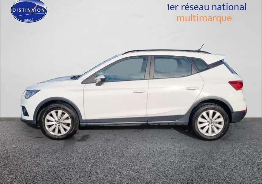 Vue latérale droite d'une SEAT Arona blanche avec jantes alliage et barres de toit noires.