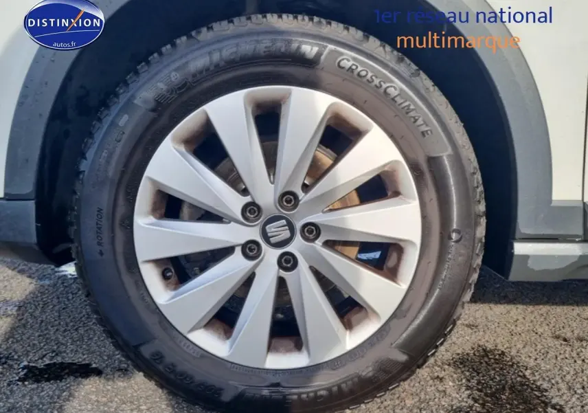 Gros plan sur la roue avant gauche d’un SEAT Arona blanc avec jante alu et pneu Michelin CrossClimate.