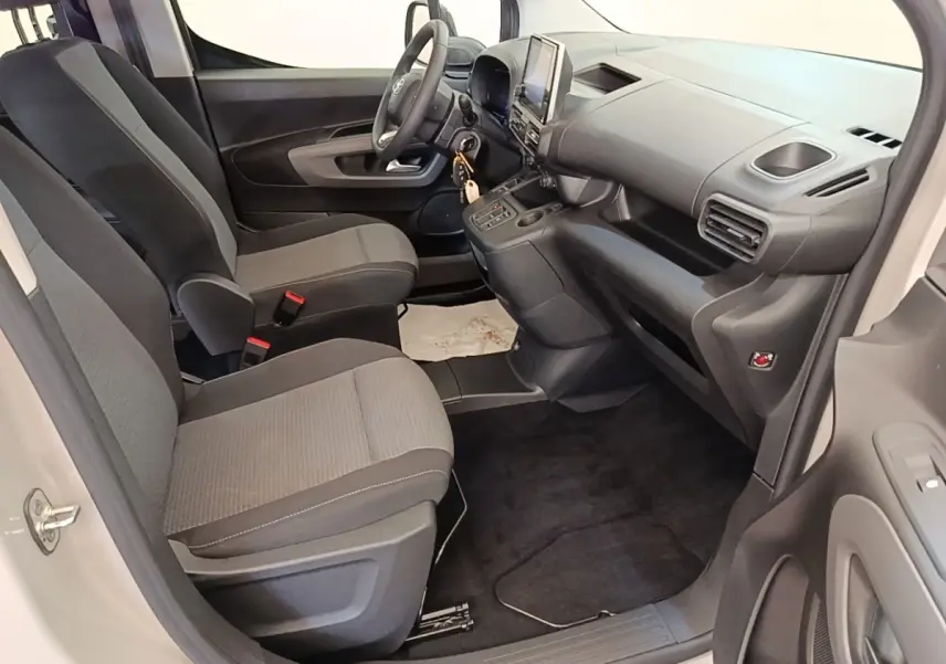 Vue intérieure côté conducteur du Toyota Proace City Verso électrique gris clair, avec tableau de bord et sièges en tissu gris.