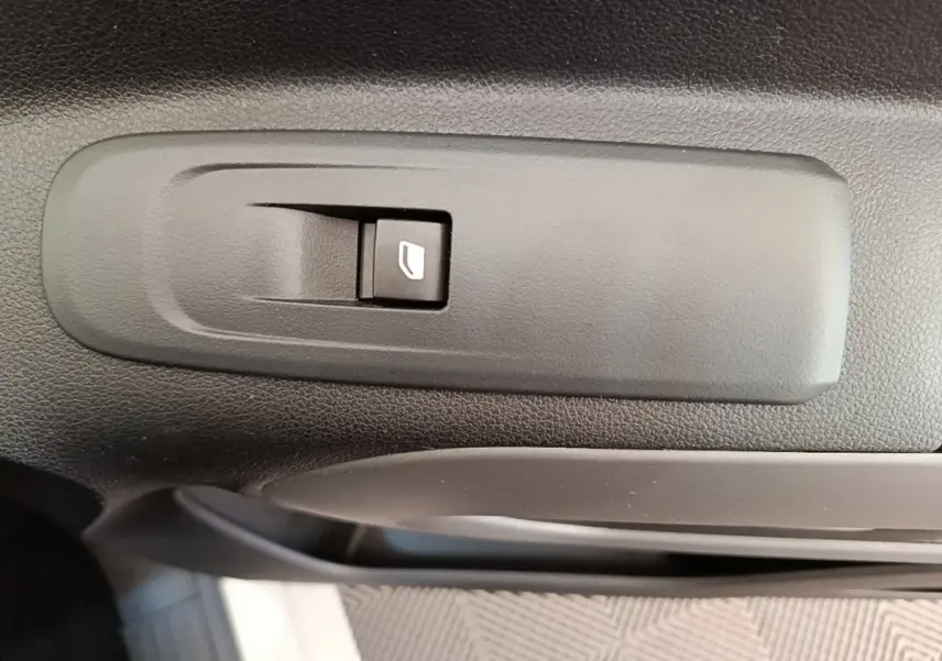 Gros plan sur le bouton de commande de lève-vitre intérieur noir dans une Toyota Proace City Verso gris clair.