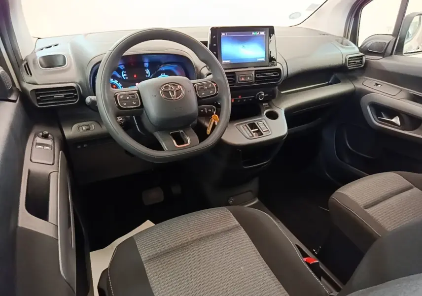 Vue intérieure avant du Toyota Proace City Verso 2022, tableau de bord noir avec écran tactile central et volant multifonction.