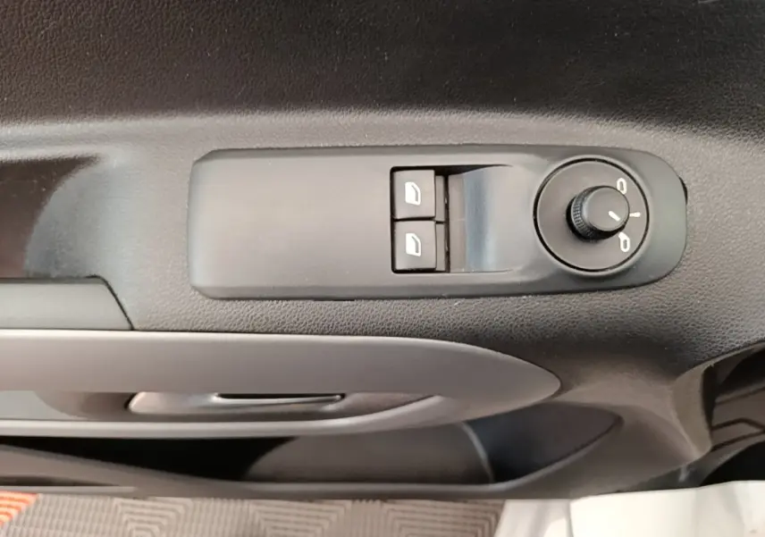 Gros plan sur les commandes de réglage des rétroviseurs et des vitres côté conducteur, intérieur noir.