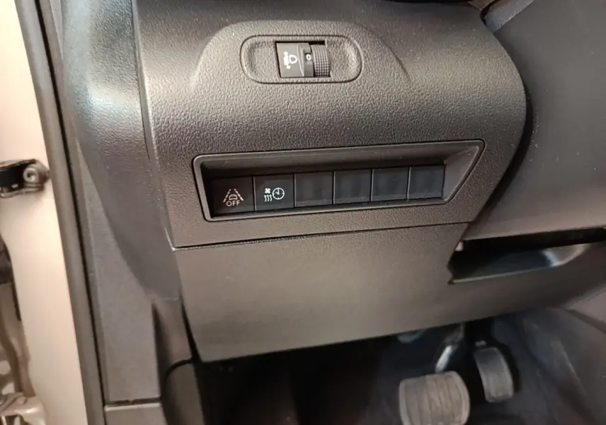 Détail intérieur côté gauche du tableau de bord gris foncé avec commandes d'assistance et pédales visibles du Toyota Proace City Verso électrique.