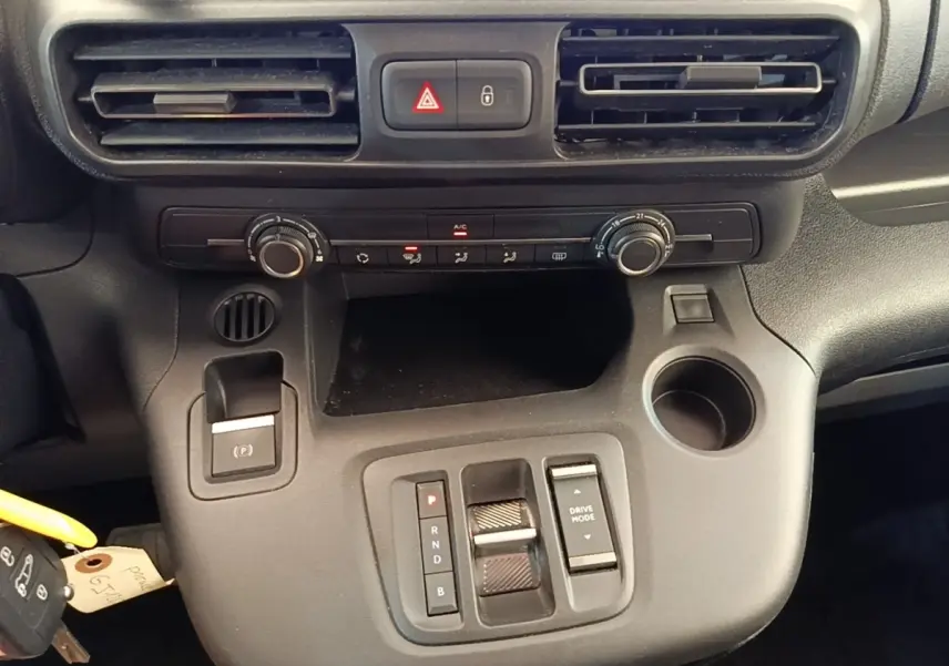 Vue rapprochée de la console centrale noire du Toyota Proace City Verso électrique, avec commandes de climatisation et boîte auto.
