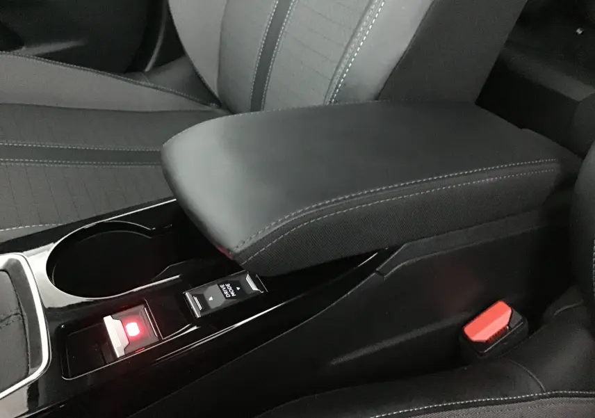 Gros plan sur l'accoudoir central noir et la console avec bouton Drive Mode du Peugeot 2008 gris platinium 2022.