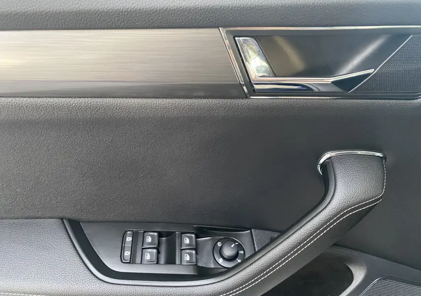 Intérieur de la porte avant gauche d'une Skoda Superb Combi 2020, avec garniture noire et poignée cuir surpiquée.