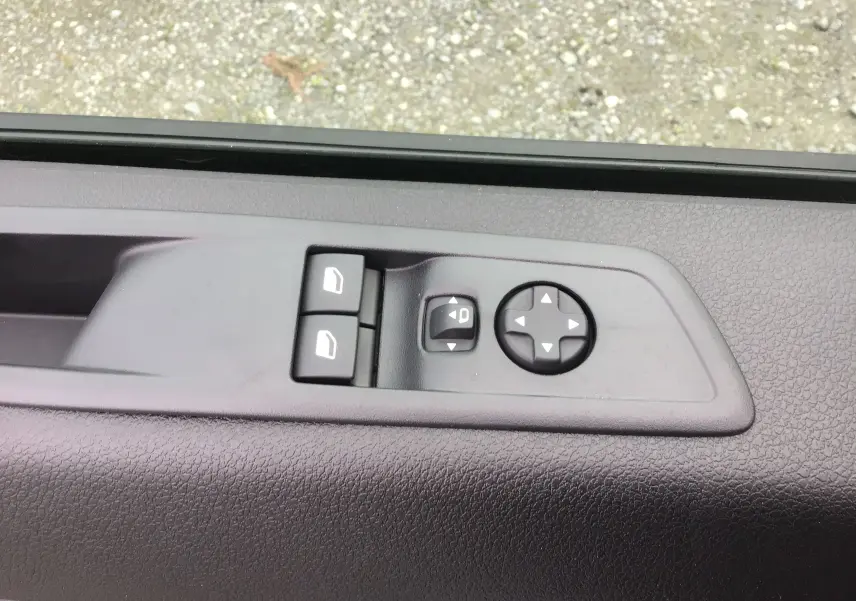 Détail des commandes de réglage des vitres et des rétroviseurs sur la porte côté conducteur d'un Citroën Jumpy blanc.