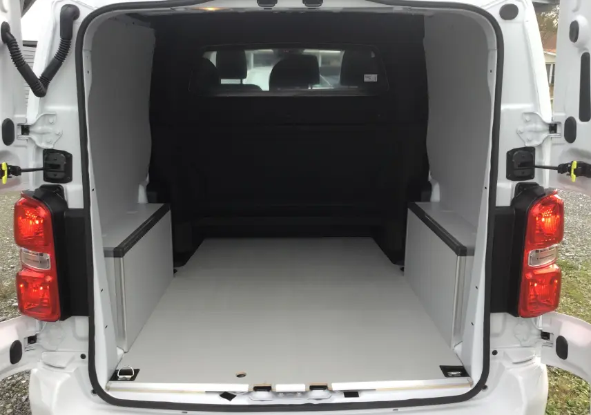 Vue arrière du Citroën Jumpy blanc avec portes ouvertes, montrant l'espace de chargement vide et aménagé.