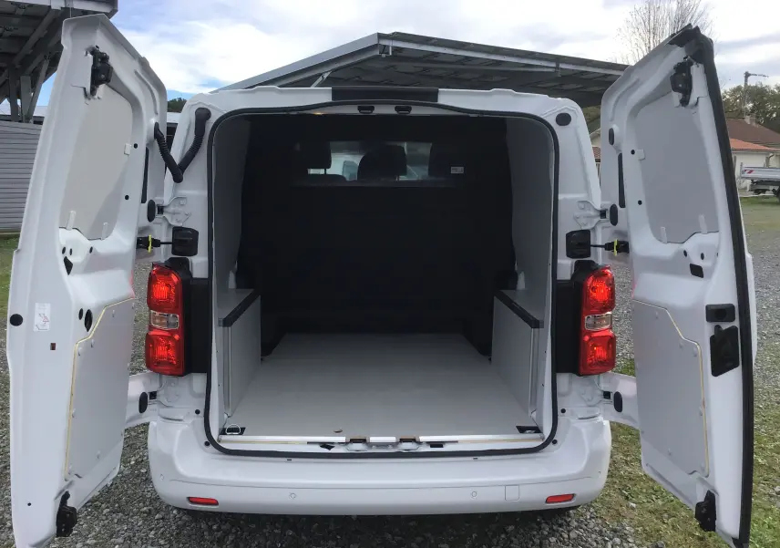Vue arrière du Citroën Jumpy blanc avec portes ouvertes dévoilant un espace de chargement vide et aménagé.