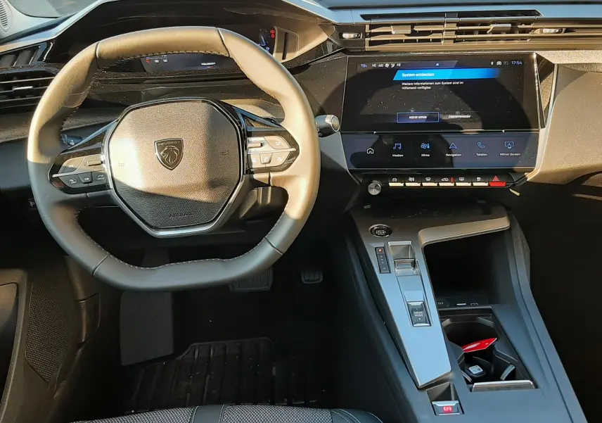 Vue intérieure de face du poste de conduite noir de la Peugeot 308 2025 avec écran tactile et volant compact.