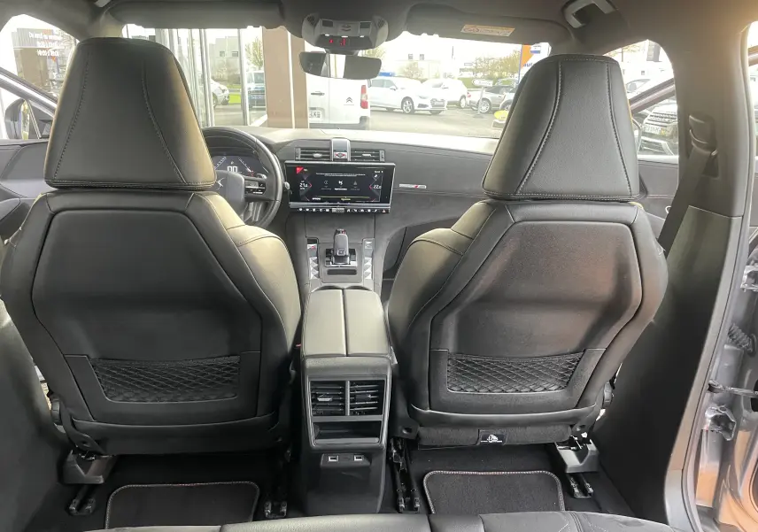 Vue arrière de l'intérieur du DS7 gris 2021, montrant les sièges avant en cuir noir et la console centrale moderne.
