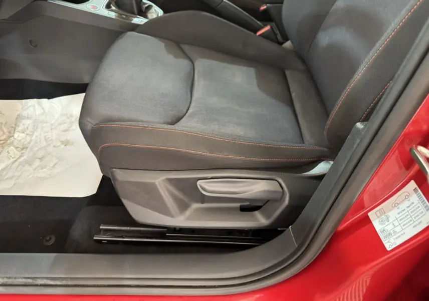 Gros plan sur le siège conducteur noir avec surpiqûres rouges d'une SEAT IBIZA 2024 rouge, porte ouverte côté gauche.